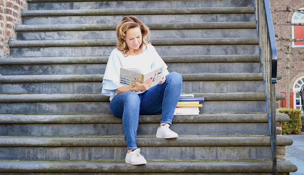 Marijke leest op een stenen trap